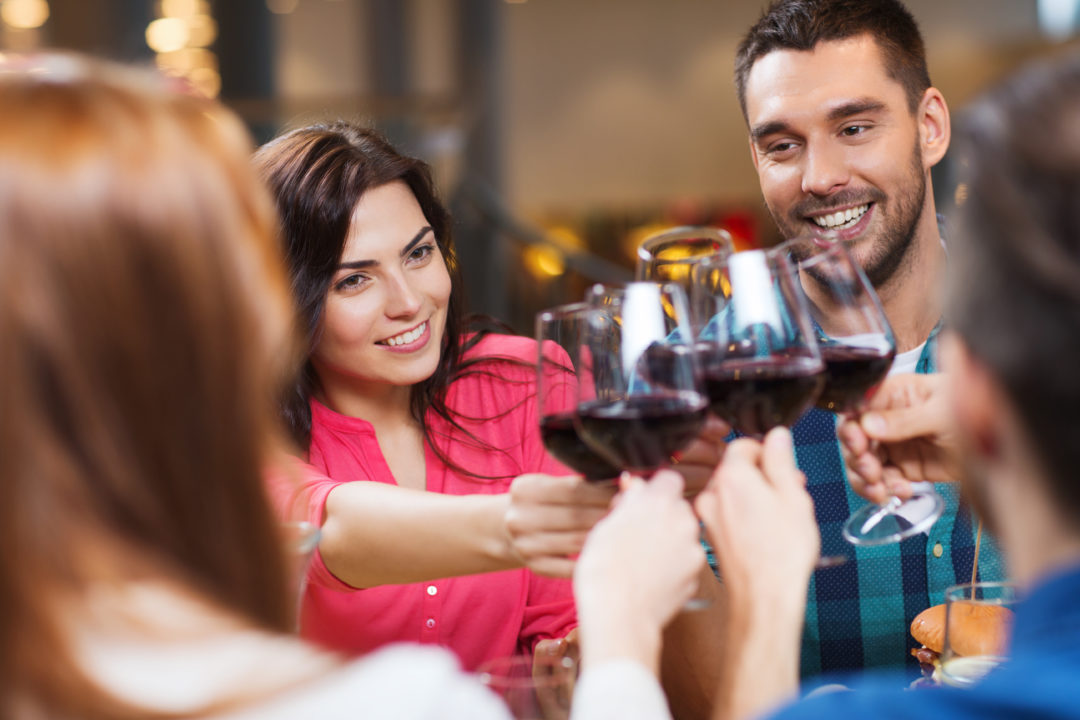 friends clinking glasses of wine at restaurant