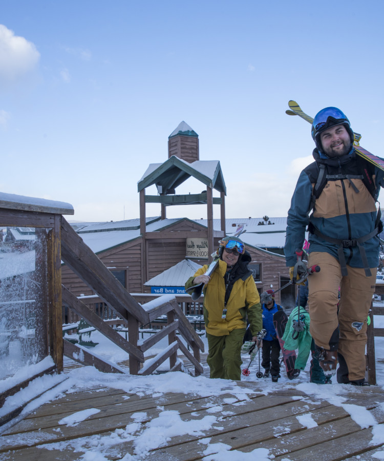 Skiers walking up base deck to ski angel fire resort